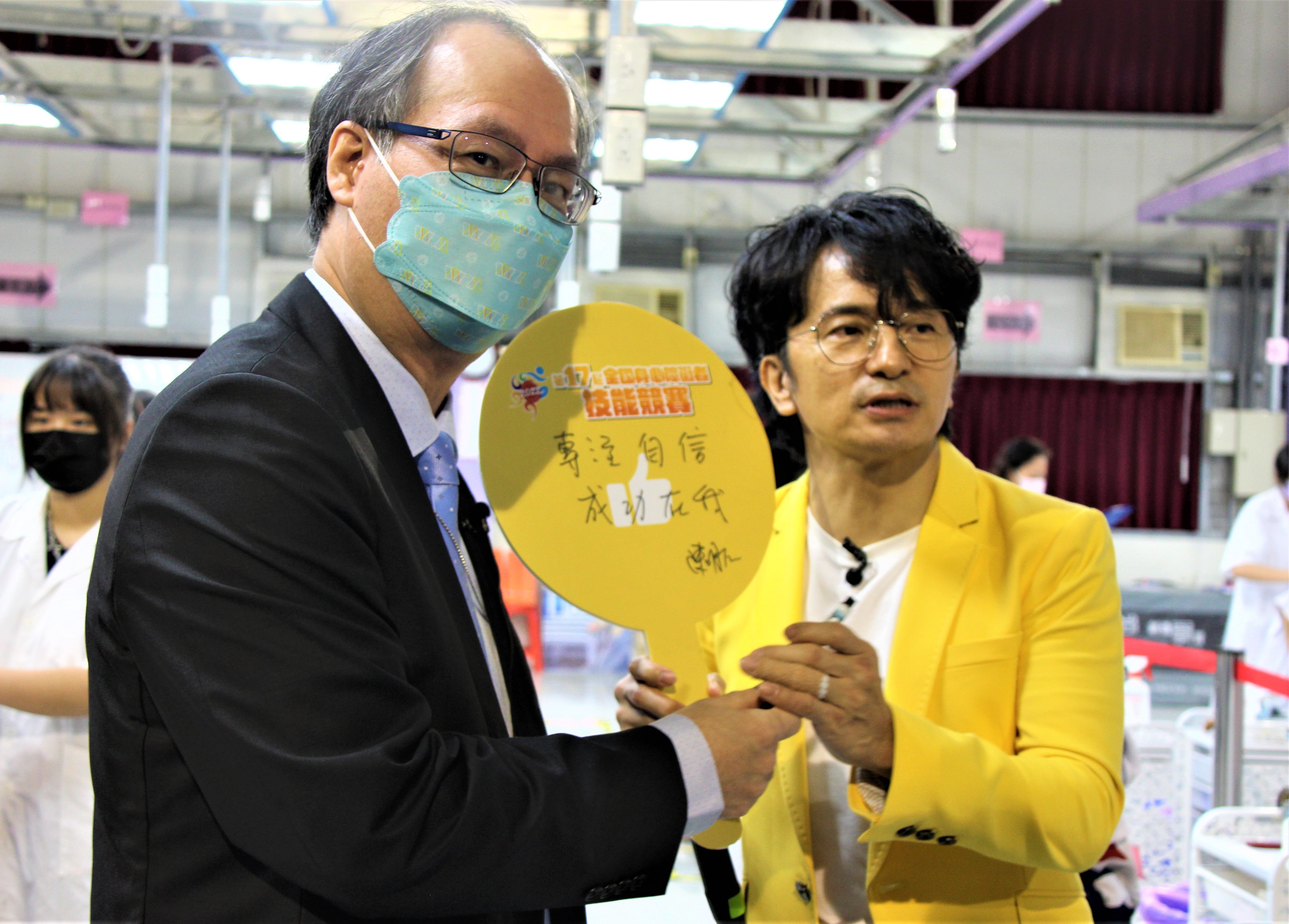 勞動部常務次長陳明仁(左)在加油板上手寫鼓勵選手的話